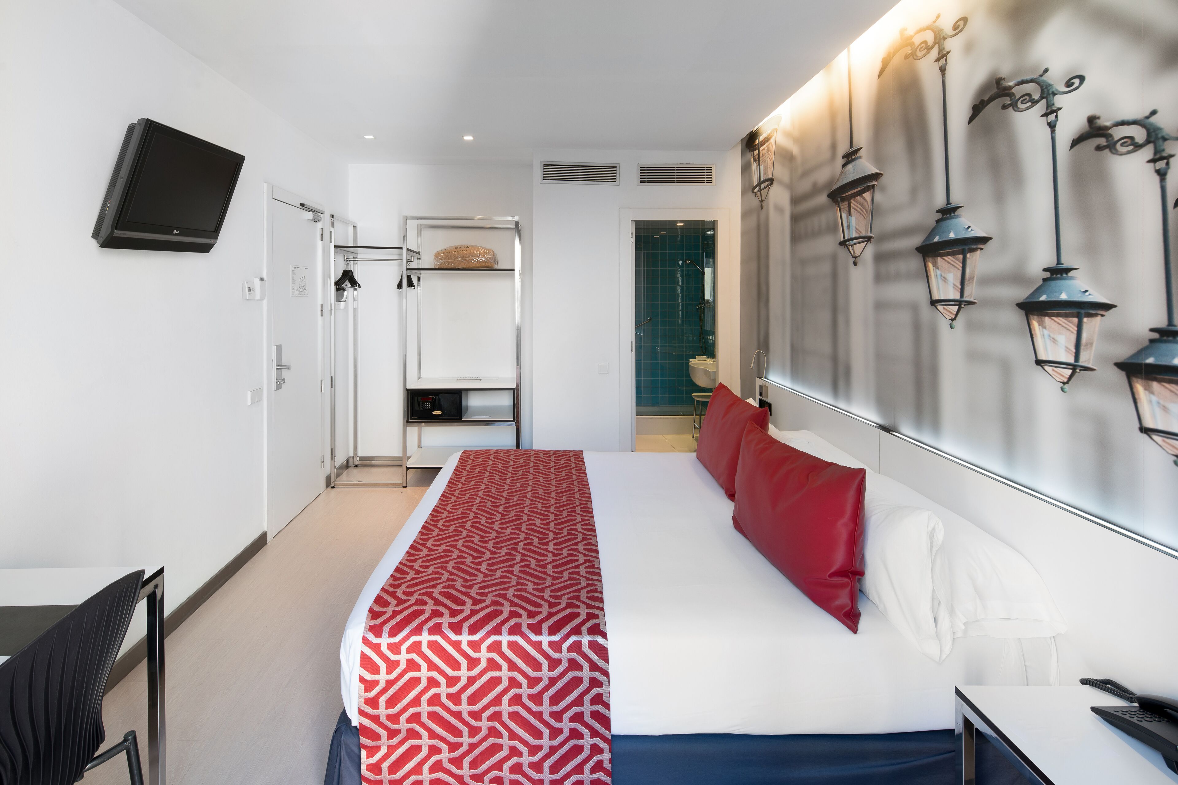 Una habitación de hotel moderna con una cama grande, un escritorio, una silla y un televisor montado en la pared.