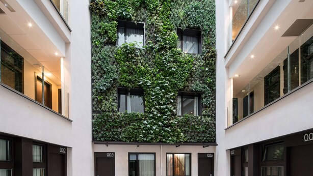 A modern building with a central courtyard featuring a variety of plants and a water feature. - Catalonia Avinyó (Barcelona)