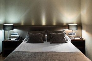 A hotel room with a large bed, two bedside tables with lamps, a nightstand, and a wall-mounted phone. - Catalonia Avinyó (Barcelona)