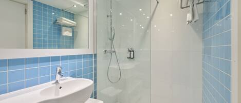 A modern bathroom with a glass-enclosed shower, a white sink, and blue-tiled walls.
