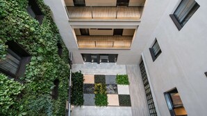 A multi-level building with a central courtyard featuring a checkered floor pattern, surrounded by balconies and a vertical garden. - Catalonia Avinyó (Barcelona)