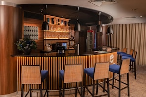 A bar area with a wooden counter, bar stools, and a variety of bottles and glasses. - Clarion Congress Hotel Olomouc (Olomouc)