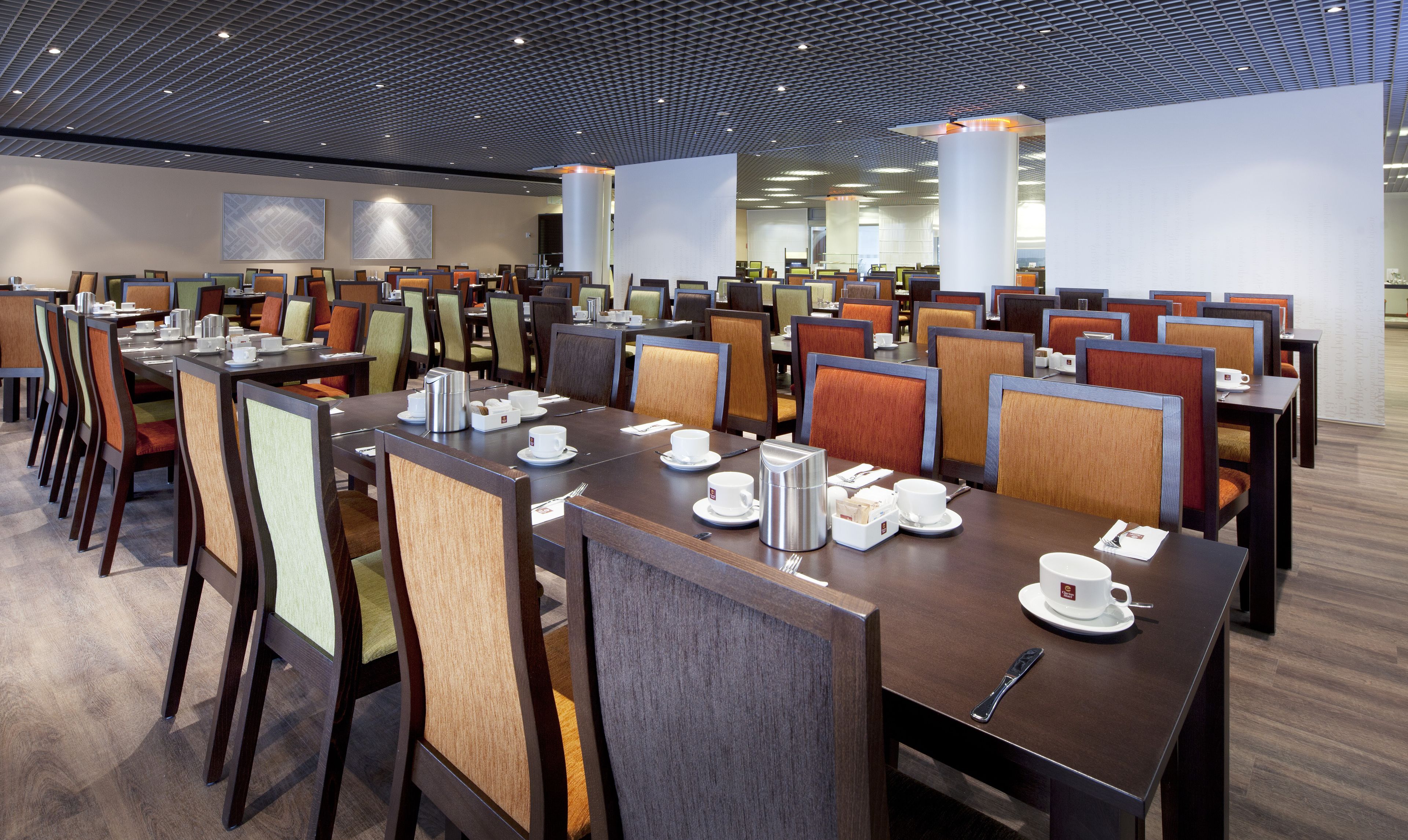A modern dining area with multiple tables and chairs, equipped with coffee makers and tea sets.