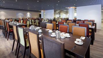 A modern dining area with multiple tables and chairs, equipped with coffee makers and tea sets.