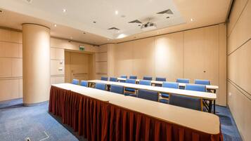 A conference room with a long table, blue chairs, and a carpeted floor.