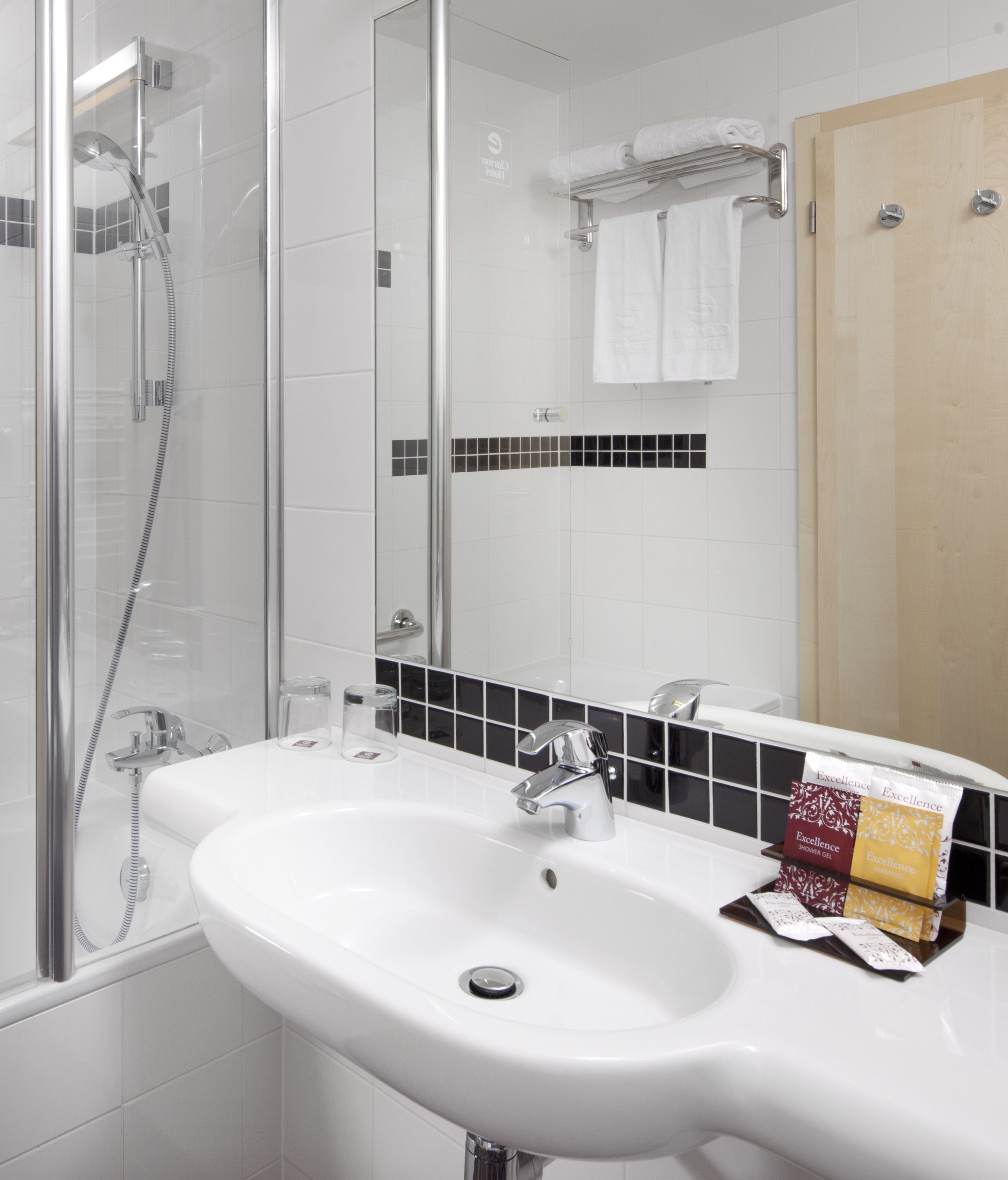 A bathroom with a glass shower enclosure, a white sink with a chrome faucet, and a mirror above the sink.