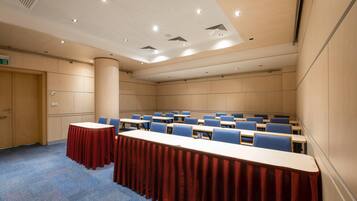 A conference room with a long table, blue chairs, and a red tablecloth.