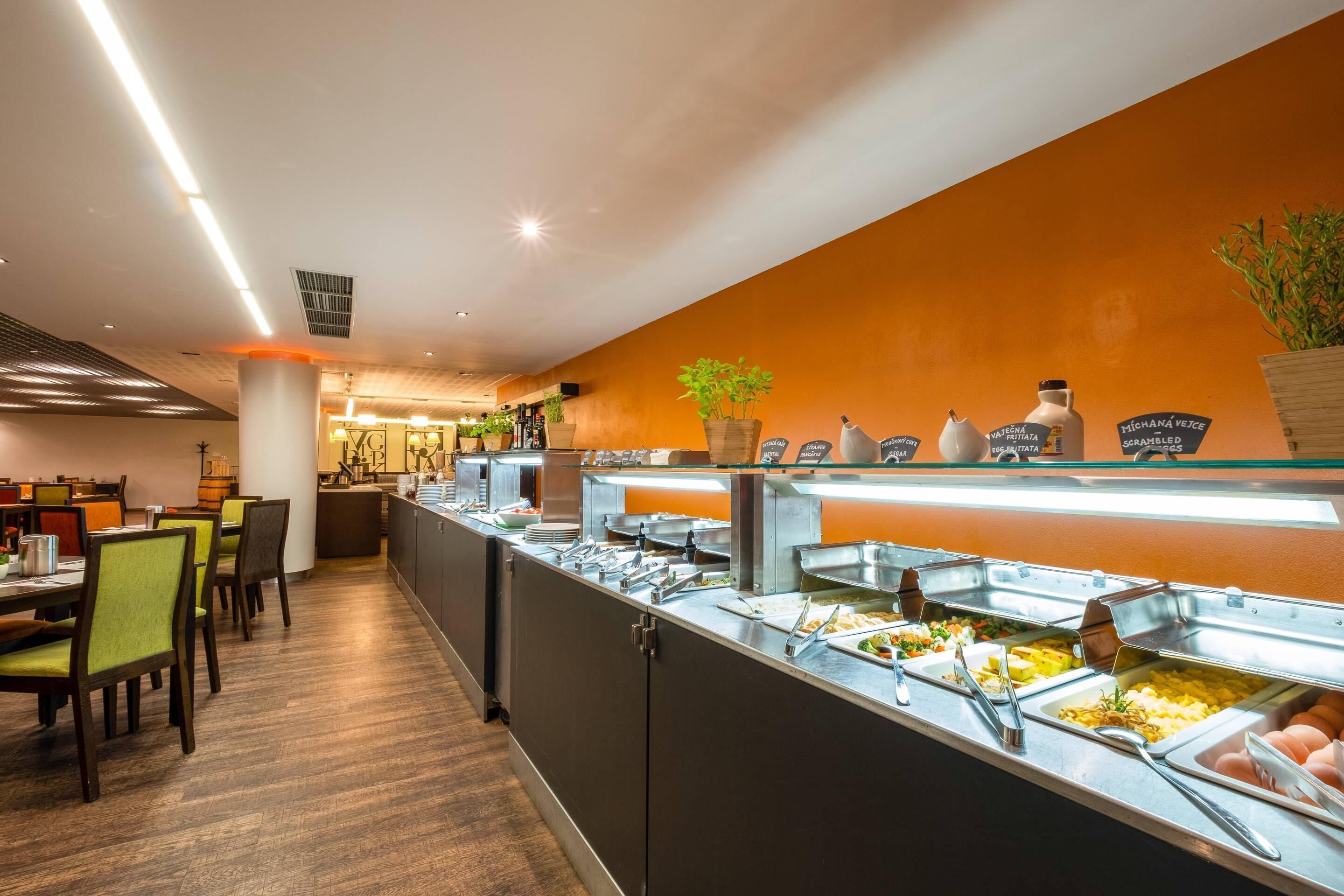 A buffet area with multiple food stations, a seating area with chairs, and a counter with a plant.