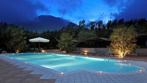 A swimming pool with a crescent moon in the sky, surrounded by trees and outdoor seating. - Hotel Villa Rizzo Resort & Spa (San Cipriano Picentino)