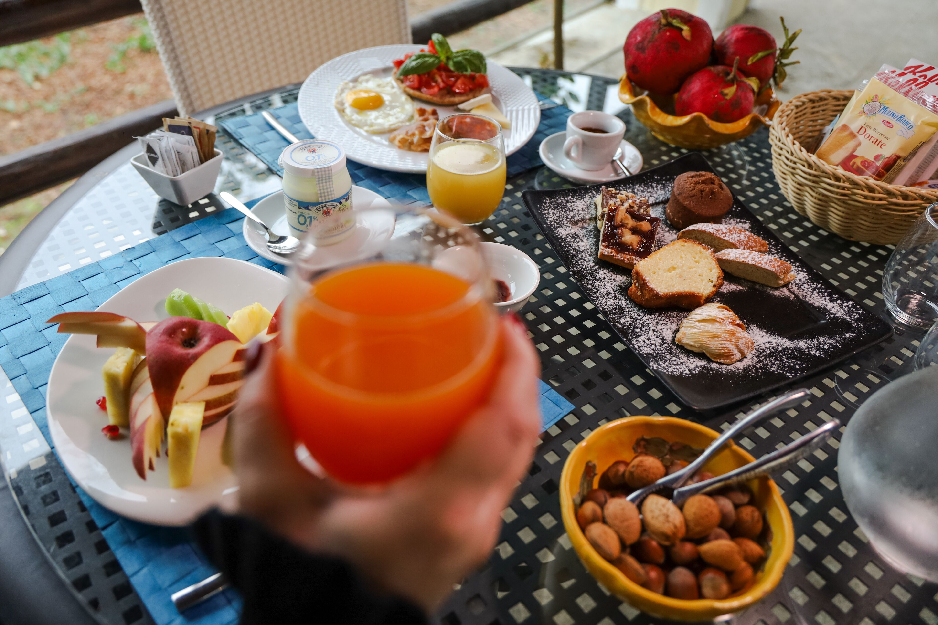 Een ontbijttafel met borden eten, een glas sinaasappelsap en een kom noten.