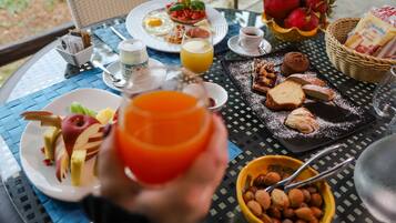 Una mesa de desayuno con platos de comida, un vaso de jugo de naranja y un tazón de nueces.