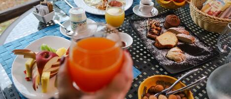 Una mesa de desayuno con platos de comida, un vaso de jugo de naranja y un tazón de nueces.