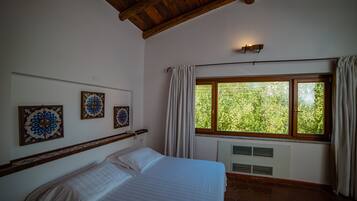 A bedroom with a bed, a window with curtains, and three wall-mounted decorative plates.