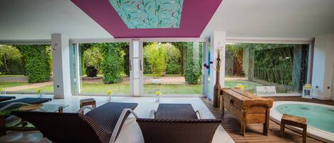 Un patio exterior moderno con mobiliario de mimbre, una mesa de madera y un letrero que dice 'VillaRizzo'.