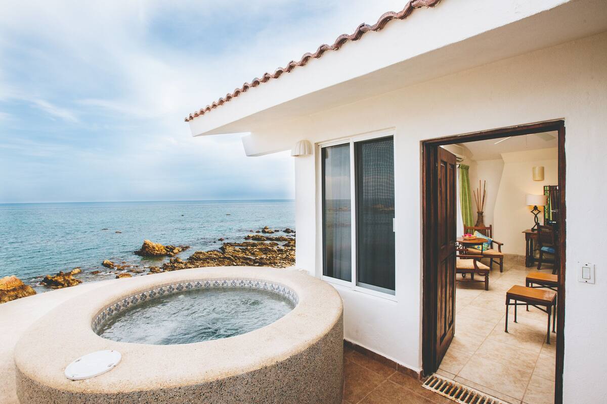 A spa area with a hot tub, a view of the sea, and a dining area with chairs and a table.