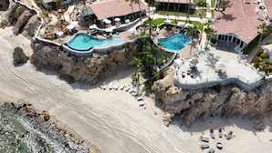 An aerial view of a coastal resort with multiple swimming pools, beachfront properties, and palm trees. - Hotel Punta Pescadero Paradise (Los Barriles)