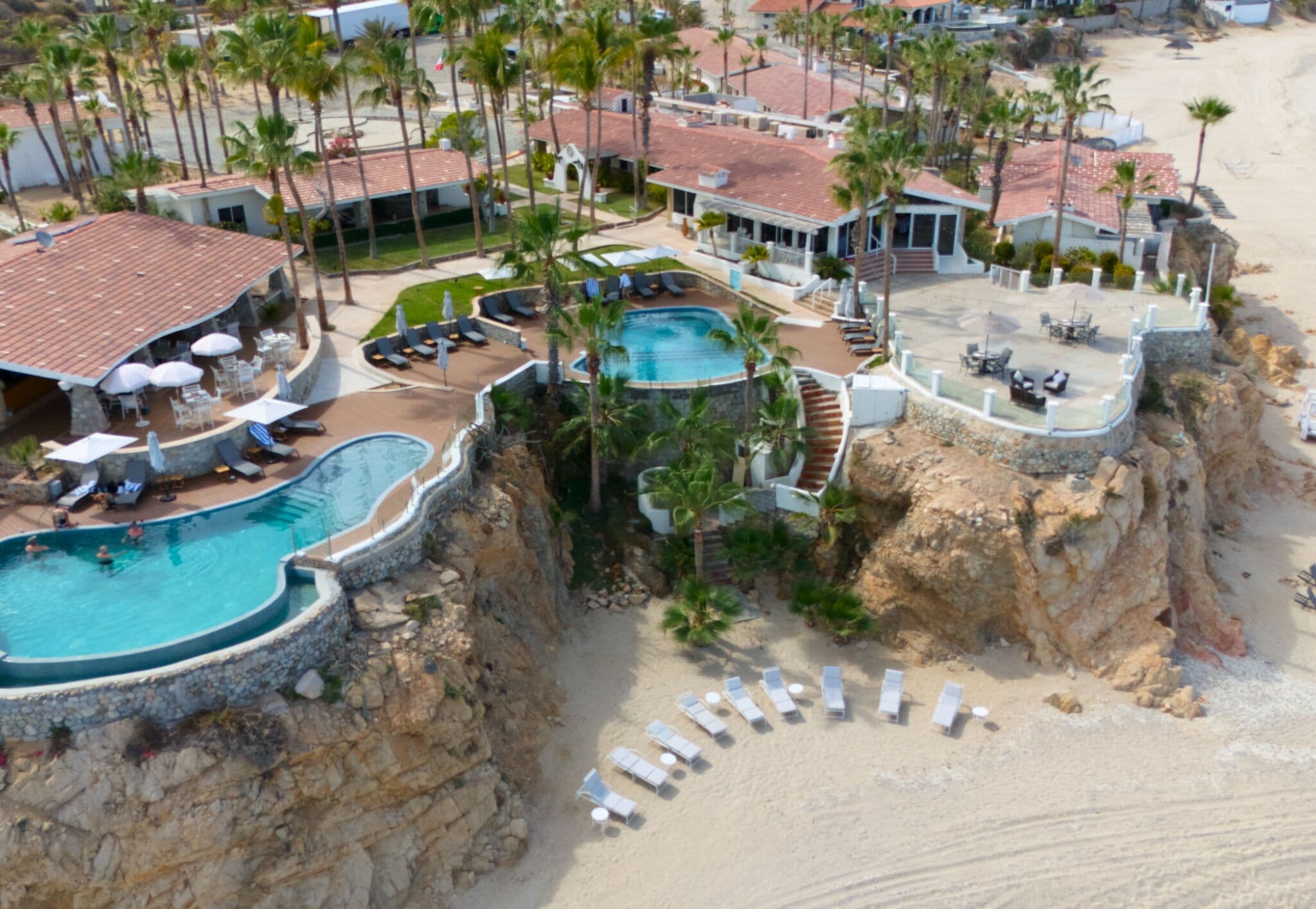 Un resort con piscina, sillas de descanso y palmeras.