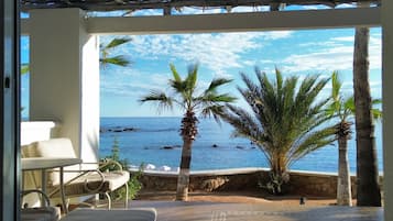 Quarto com vista para o mar, uma parede de pedra e uma palmeira.