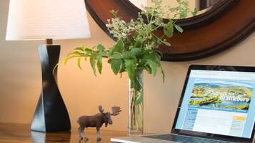A laptop on a wooden desk with a lamp and a small plant beside it.