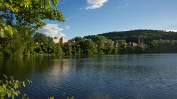 A calm lake with buildings on a hill in the background.