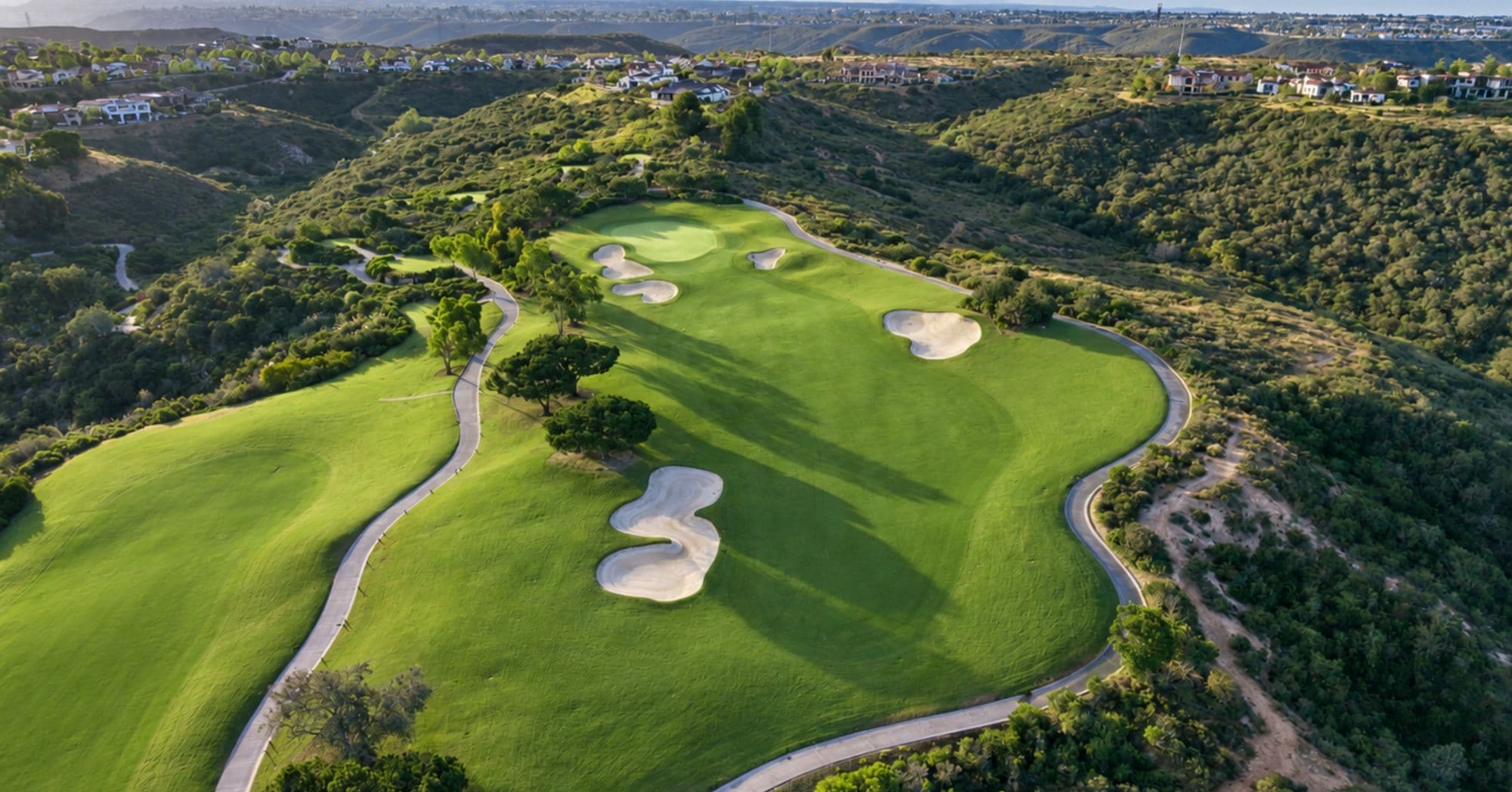 A golf course with sand bunkers and a winding path.