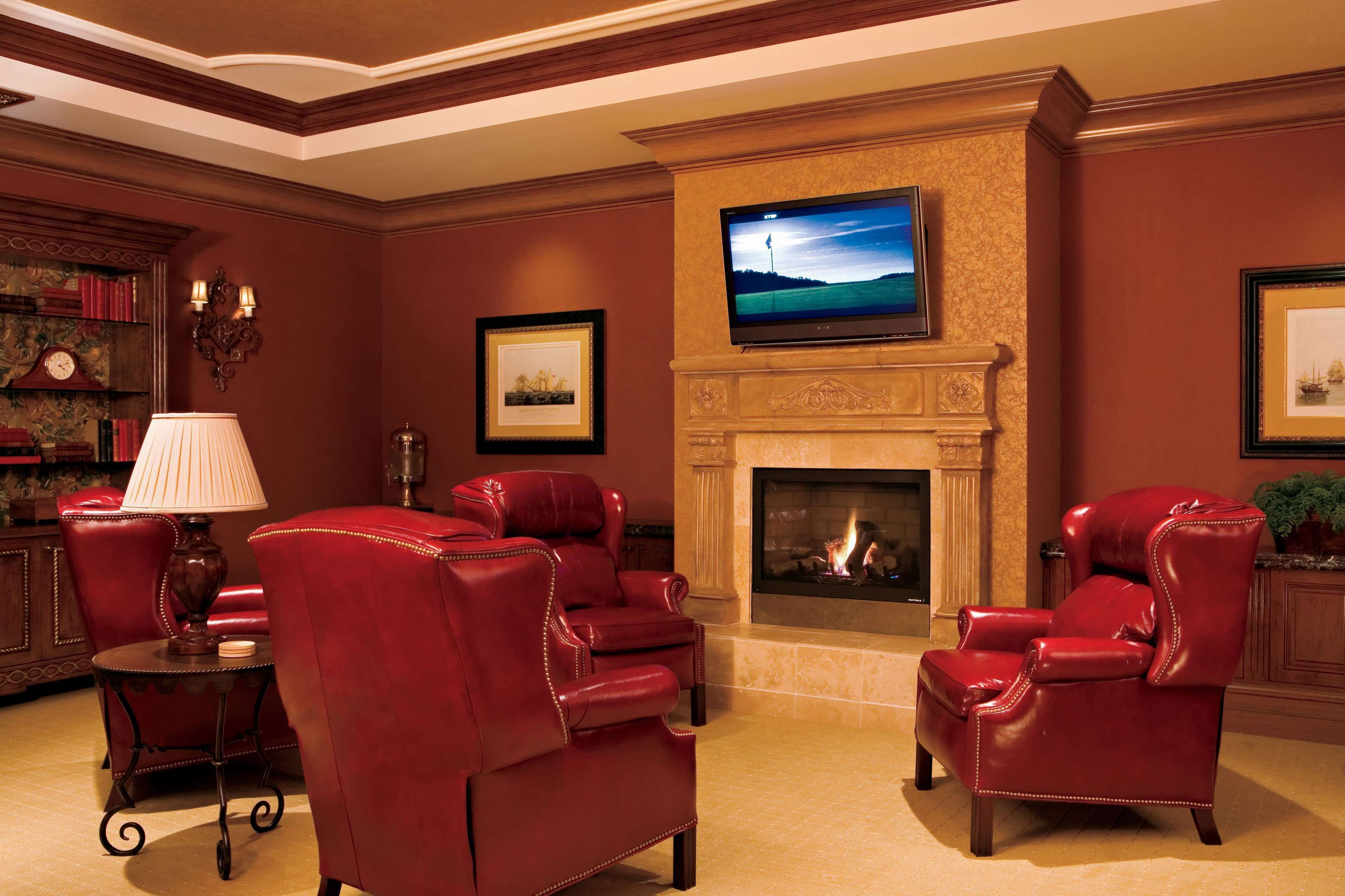 Una habitación con chimenea, sillones de cuero, televisor y estantería.