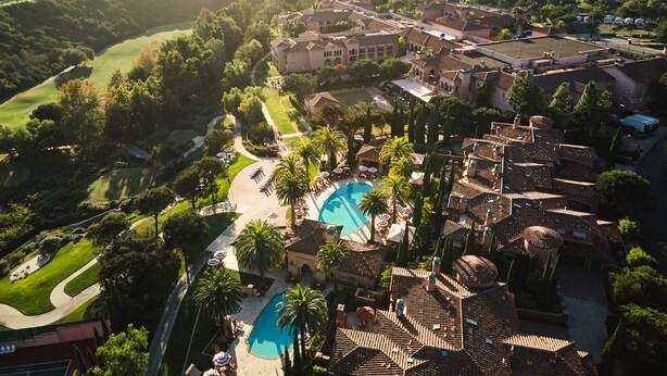 A resort with a large swimming pool, multiple buildings, and surrounding greenery.