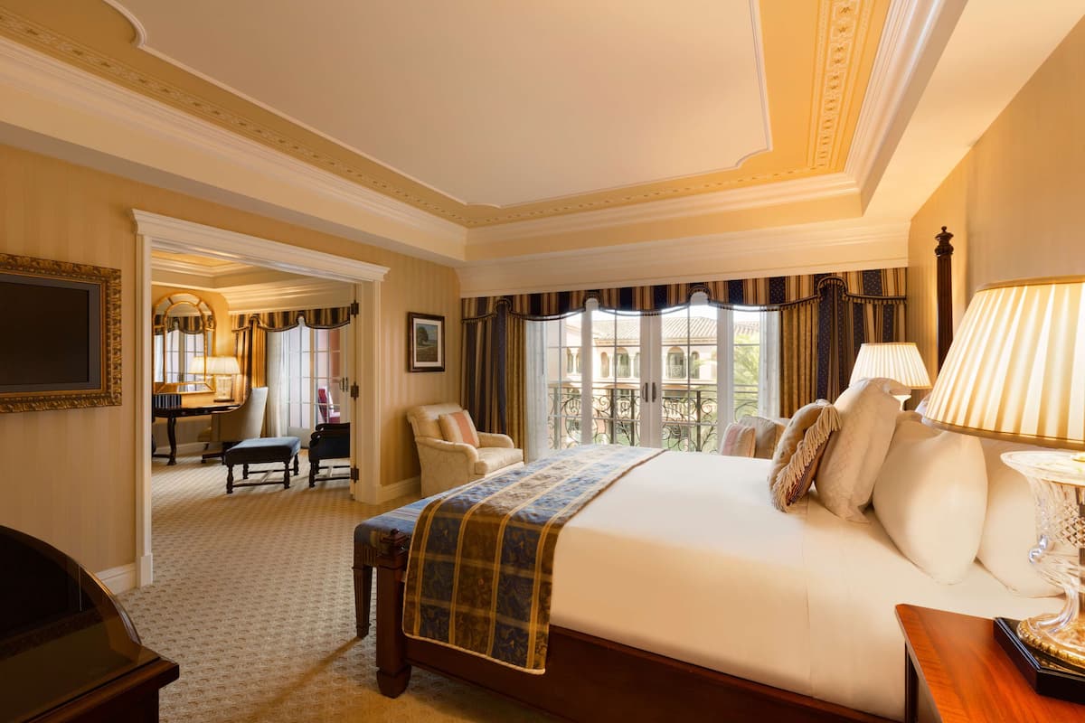 A spacious hotel room with a large bed, a desk, and a view of the outdoors.
