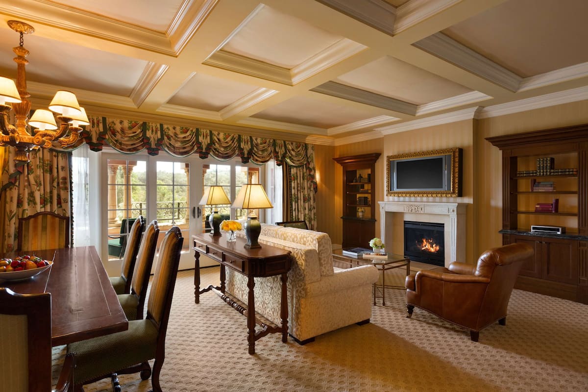 A formal living room with a fireplace, a television, and a dining area with chairs and a table.