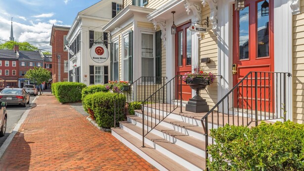 A historic building with a red door, a welcome sign, and a brick pathway leading to the entrance. - Essex Street Inn & Suites, an Ascend Collection Hotel (Newburyport)