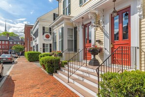 A historic building with a red door, a welcome sign, and a brick pathway leading to the entrance. - Essex Street Inn & Suites, an Ascend Collection Hotel (Newburyport)