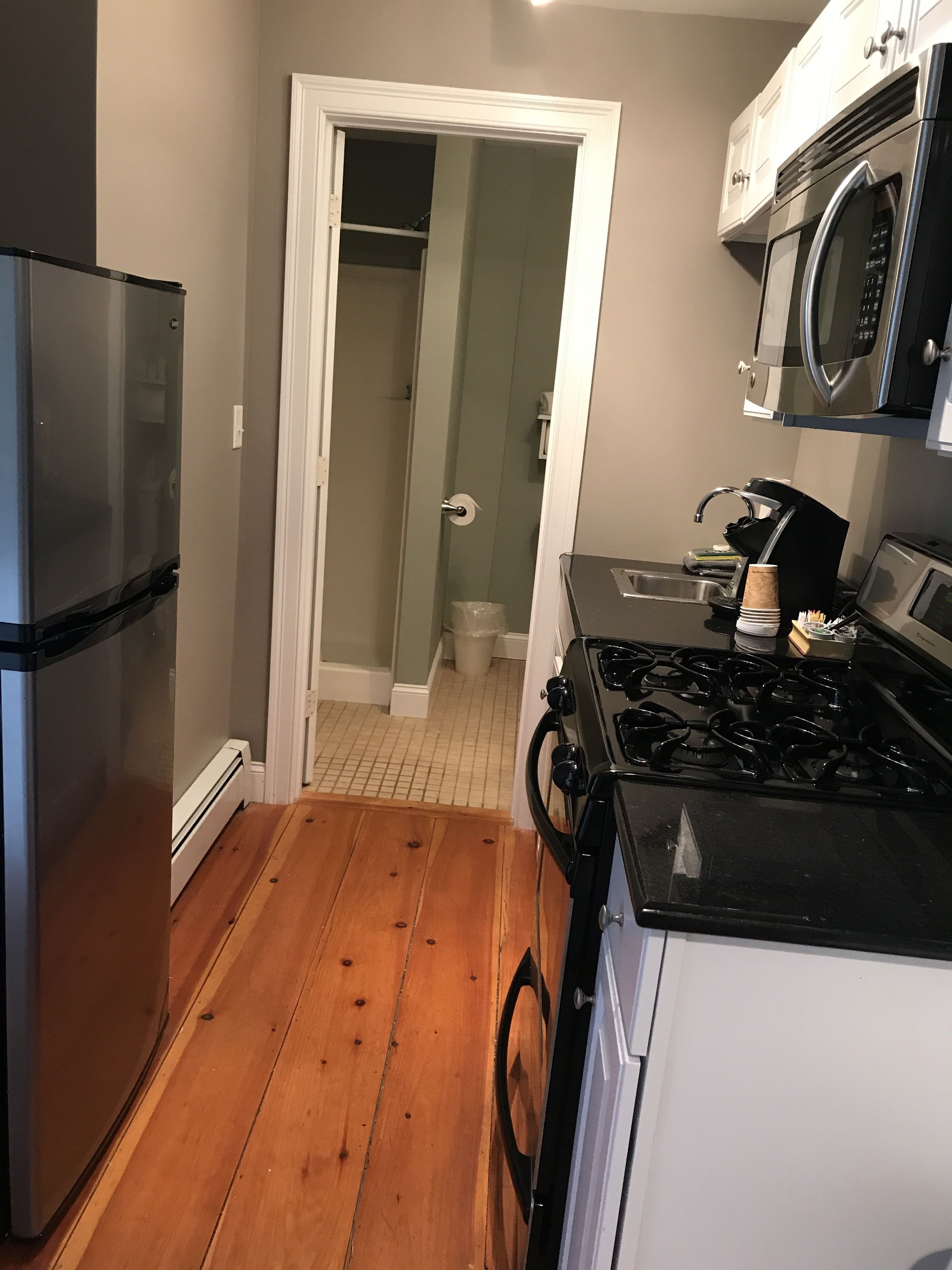 A compact kitchen with a refrigerator, stove, microwave, and a small sink.