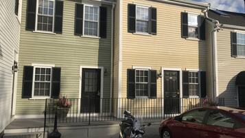 A row of townhouses with a motorcycle parked in front and a red car parked on the street.