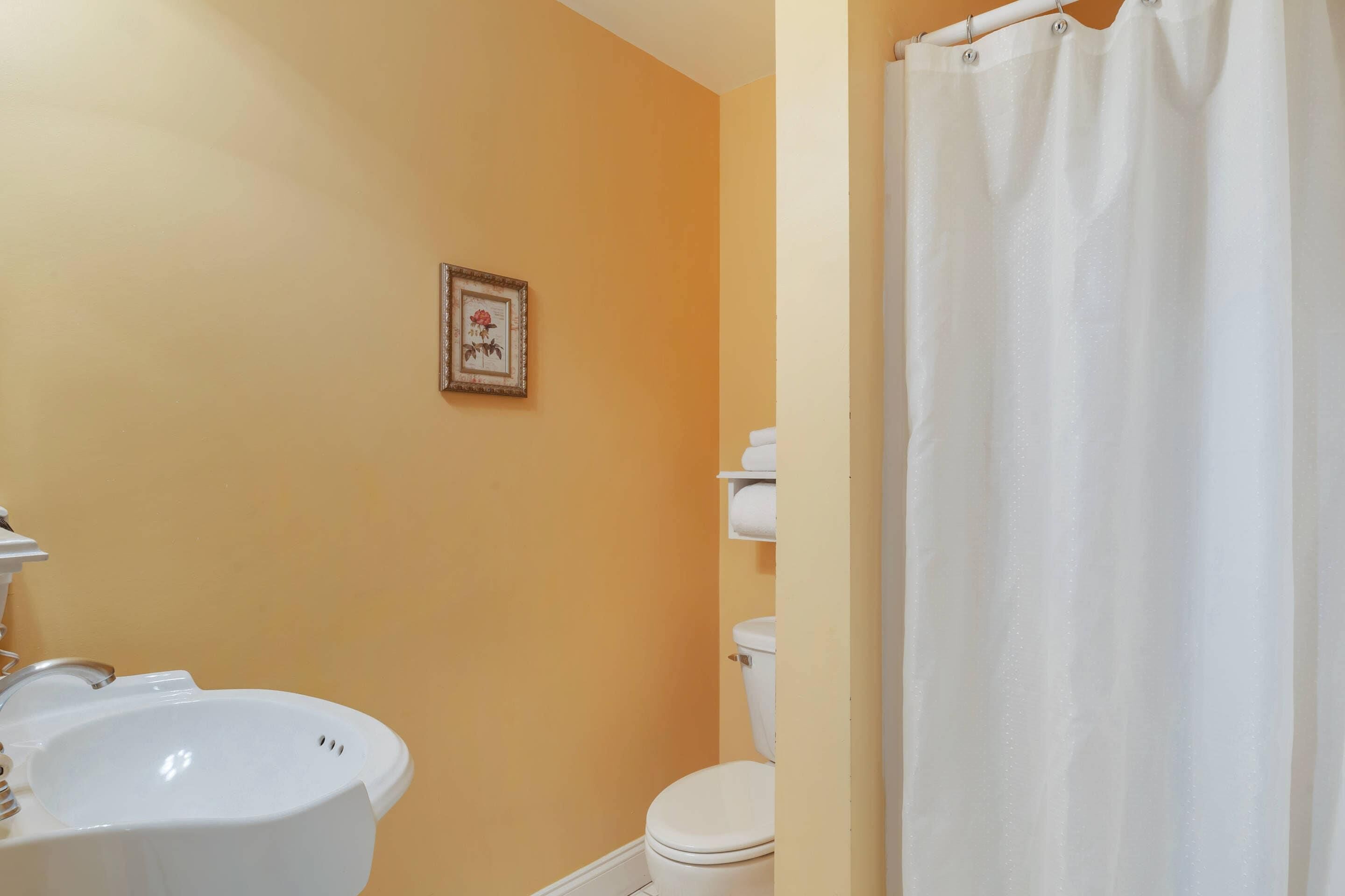 Un baño con lavamanos, inodoro y cortina de ducha blancos.