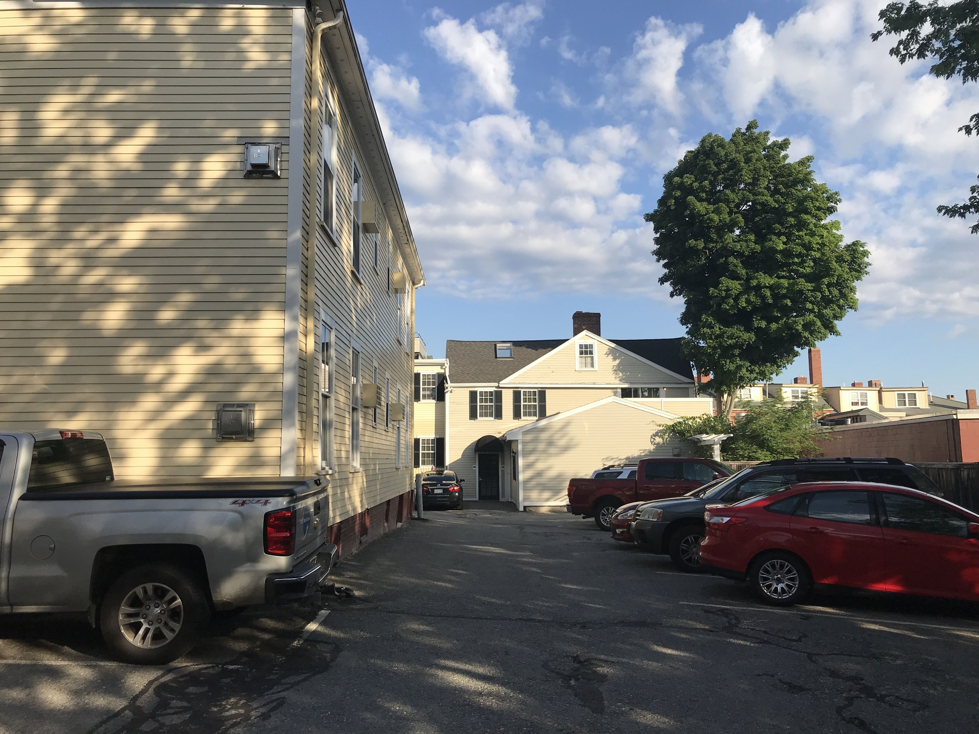 A street view with parked cars and a building with a garage entrance.