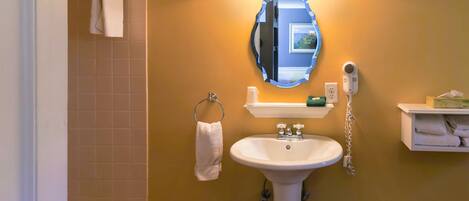 A bathroom with a sink, mirror, towel rack, and a wall-mounted hairdryer.