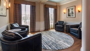 A modern living room with leather sofas, a round rug, and a cityscape view through patterned curtains. - Essex Street Inn & Suites, an Ascend Collection Hotel (Newburyport)