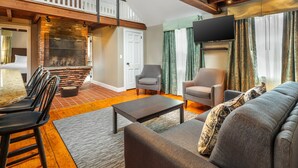 A spacious living room with a fireplace, a dining area with a table and chairs, and a comfortable seating area with a sofa and armchairs. - Essex Street Inn & Suites, an Ascend Collection Hotel (Newburyport)