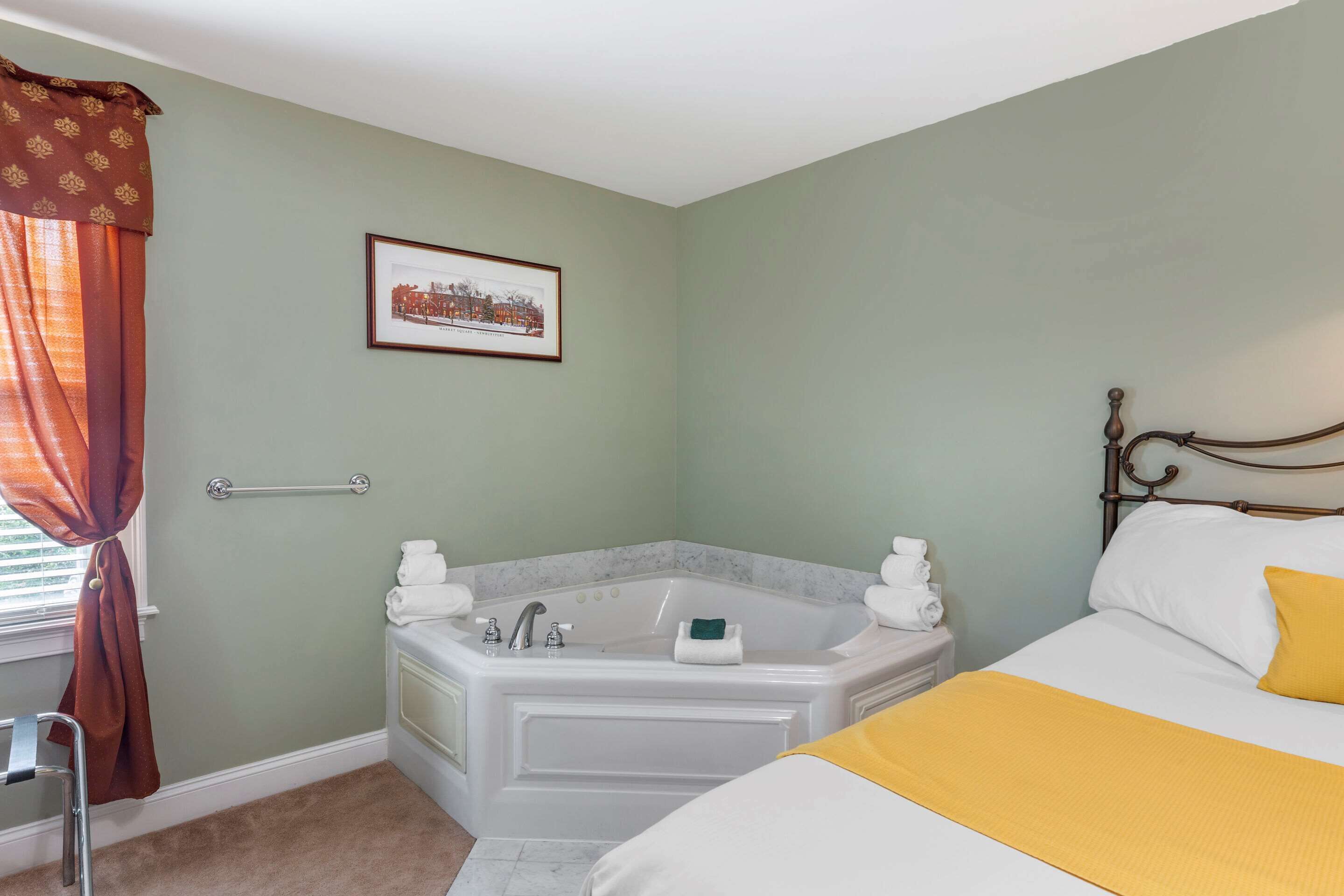 Une chambre avec un grand lit, une baignoire et un fauteuil accessible aux personnes en fauteuil roulant.