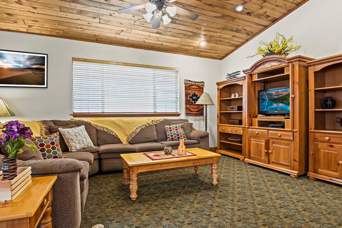 A cozy living room with a wooden ceiling, a sofa, a coffee table, and built-in wooden cabinets.