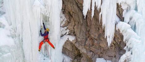 Una persona escalando hielo en una cascada congelada.