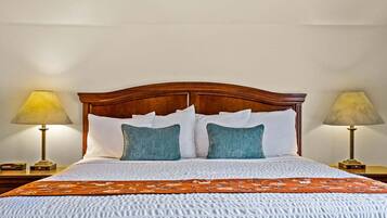 A neatly made bed with a wooden headboard, white and teal pillows, and an orange bedspread.