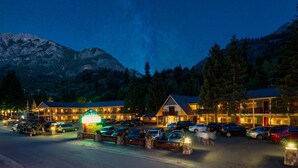 Un hotel con varias construcciones, un estacionamiento y montañas al fondo.