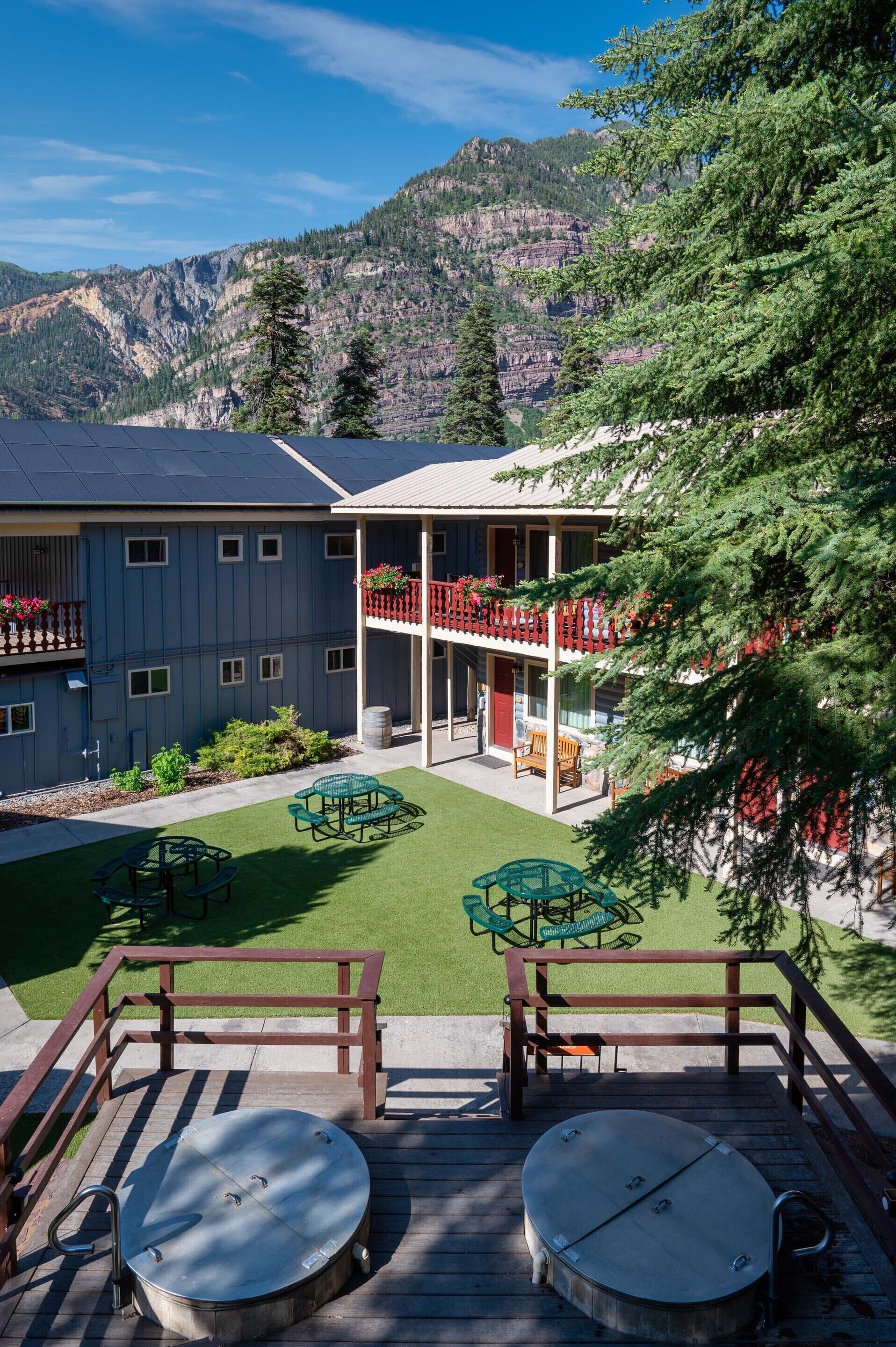 A building with a patio area, outdoor seating, and a view of mountains.