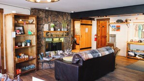 Un vestíbulo acogedor con chimenea, estanterías de madera, un sofá de cuero y un televisor.