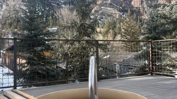 Un jacuzzi en una terraza de madera con vistas a la montaña.