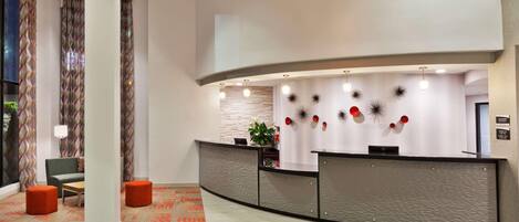 A modern reception area with a curved desk, seating, and decorative wall art.