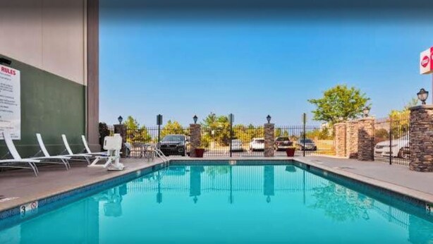 A swimming pool with lounge chairs, a stone wall, and a fence. - Sonesta Essential Columbus (Columbus)