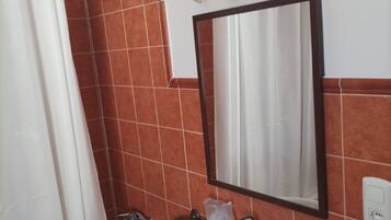 Een badkamer met een wit wastafel, een spiegel en een douchegordijn.