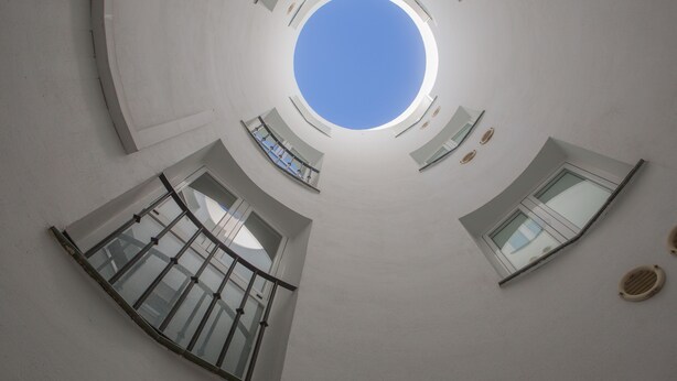 A circular atrium with a skylight, multiple balconies, and a central open space. - Hostal San Cayetano (Ronda)